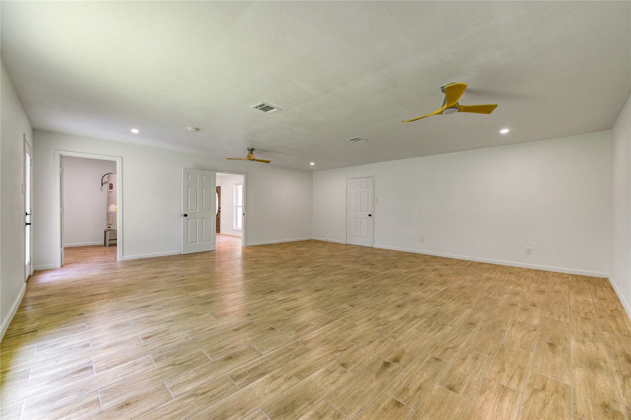 5411 Logston Lane Spring, TX 77389 - Photo 43 of 50 Spacious room featuring elegant wood-look flooring, two modern ceiling fans, and ample natural light from multiple entry points.