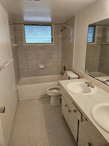 a bathroom with a granite countertop sink a toilet a mirror and bathtub