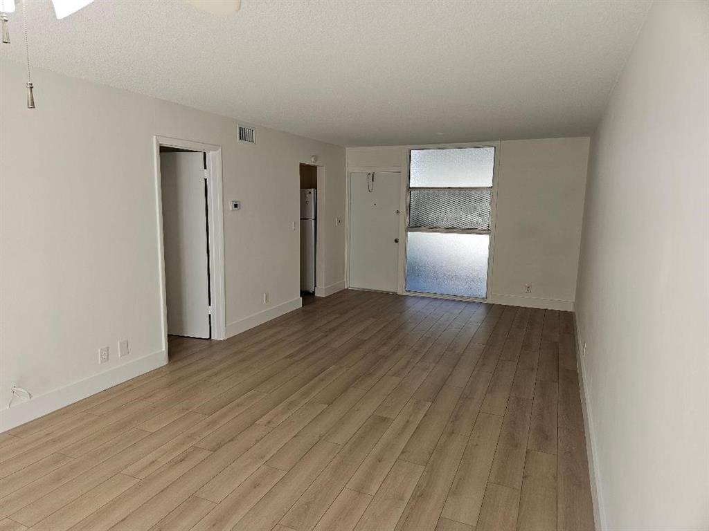 777 Southeast 2nd Avenue, Unit D123 Deerfield Beach, FL 33441 - Photo 4 of 36 a view of an empty room with wooden floor and a window