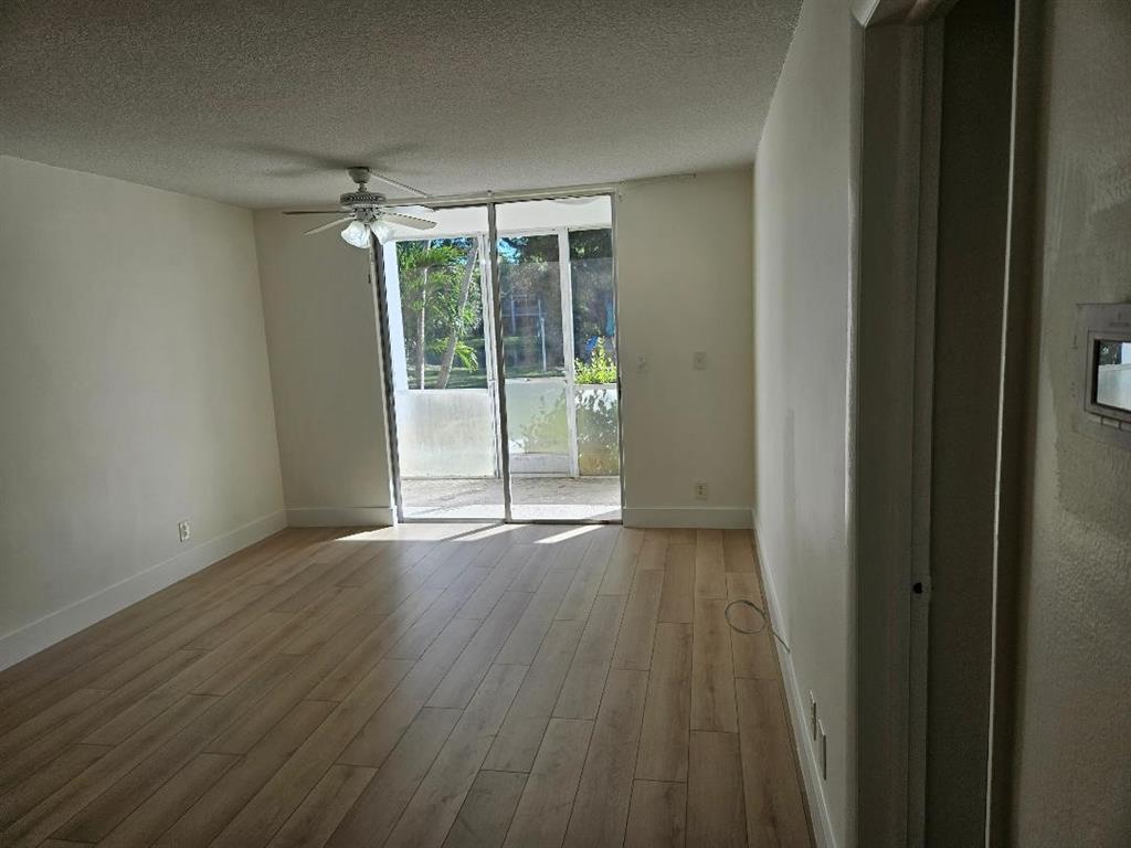 777 Southeast 2nd Avenue, Unit D123 Deerfield Beach, FL 33441 - Photo 6 of 36 a view of an empty room with wooden floor and a window