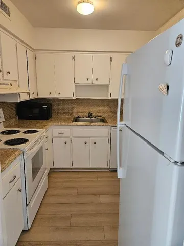 a kitchen with granite countertop white cabinets and white appliances
