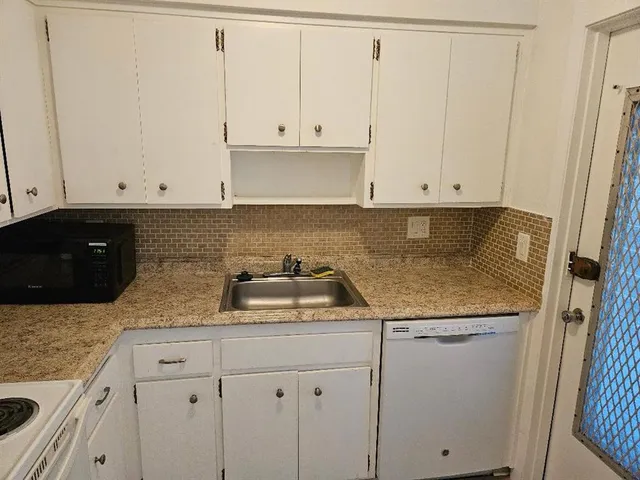 a kitchen with granite countertop white cabinets and sink