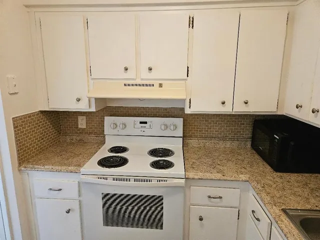 a kitchen with a stove and white cabinets