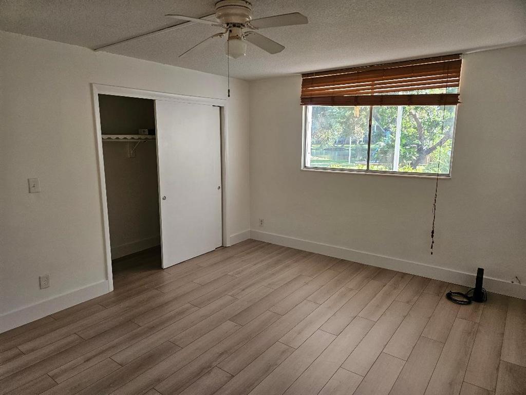 777 Southeast 2nd Avenue, Unit D123 Deerfield Beach, FL 33441 - Photo 10 of 36 a view of an empty room with wooden floor and a window