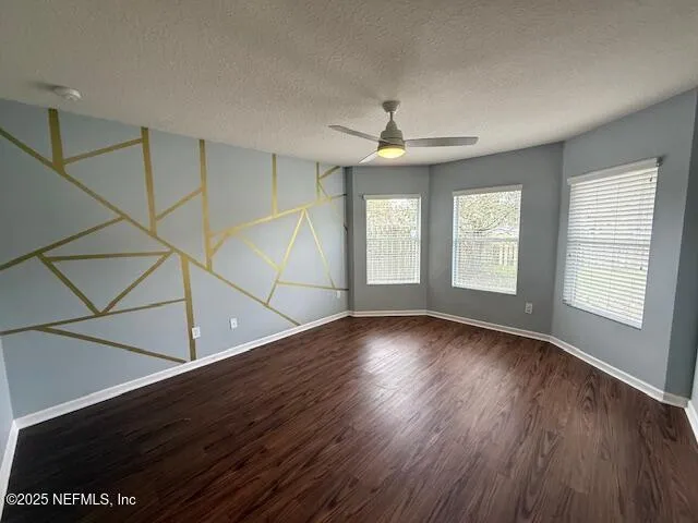 an empty room with wooden floor chandelier and windows