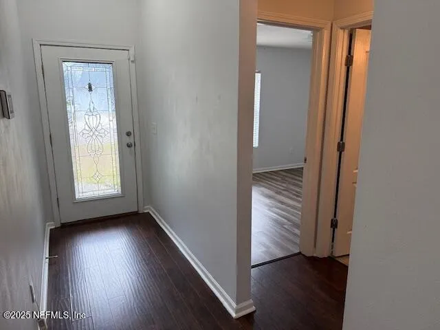 an empty room with wooden floor closet and windows