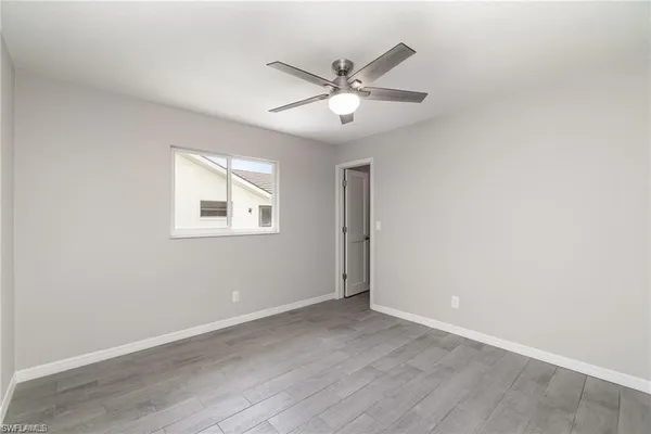 an empty room with wooden floor fan and windows
