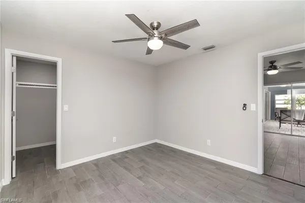 an empty room with wooden floor and ceiling fan
