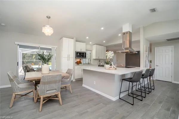 a kitchen with a dining table chairs and wooden floor