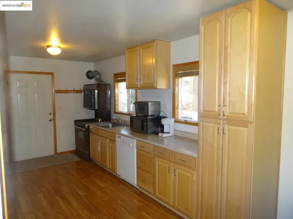a kitchen with stainless steel appliances granite countertop a refrigerator a sink dishwasher and wooden cabinets with wooden floor