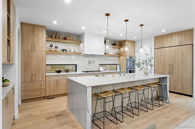 a kitchen with kitchen island a stove a refrigerator a sink and a oven with wooden floor