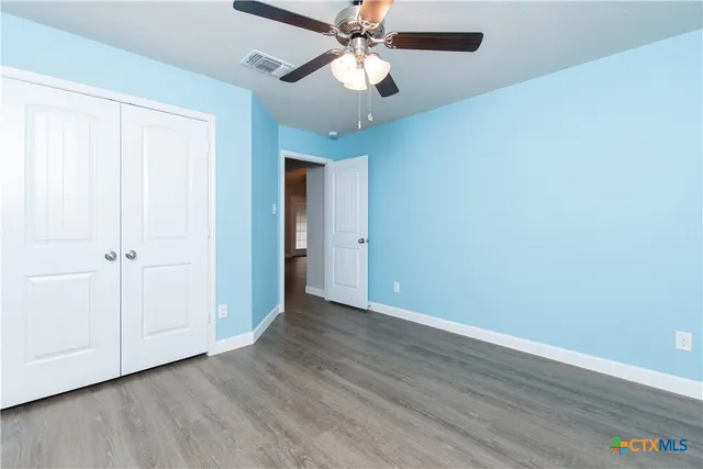 an empty room with wooden floor a ceiling fan and entryway
