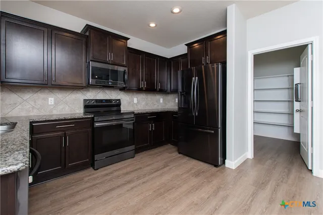 a kitchen with stainless steel appliances granite countertop a refrigerator and a stove top oven
