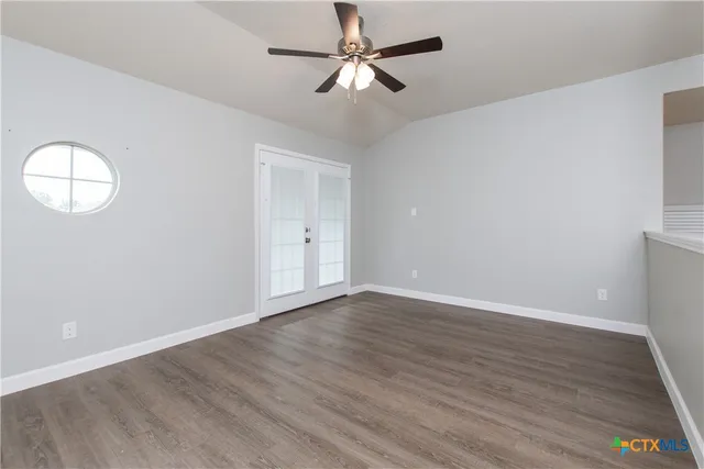 an empty room with wooden floor and windows