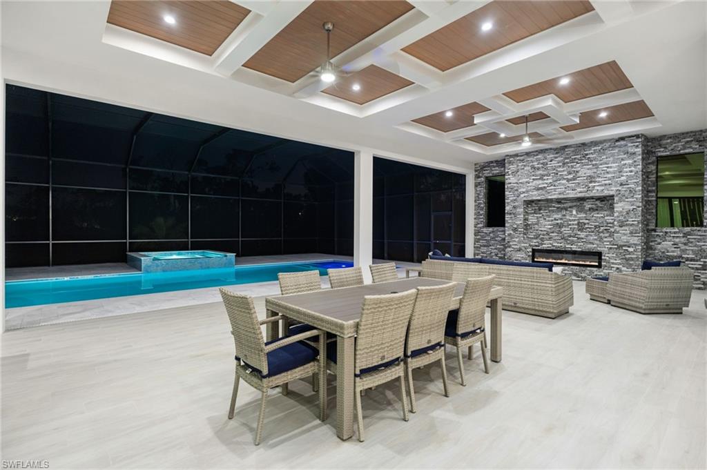 7040 Sable Ridge Lane Naples, FL 34109 - Photo 41 of 50 Summer kitchen, and covered lounge area with fireplace—perfect for gatherings or relaxed al fresco dining