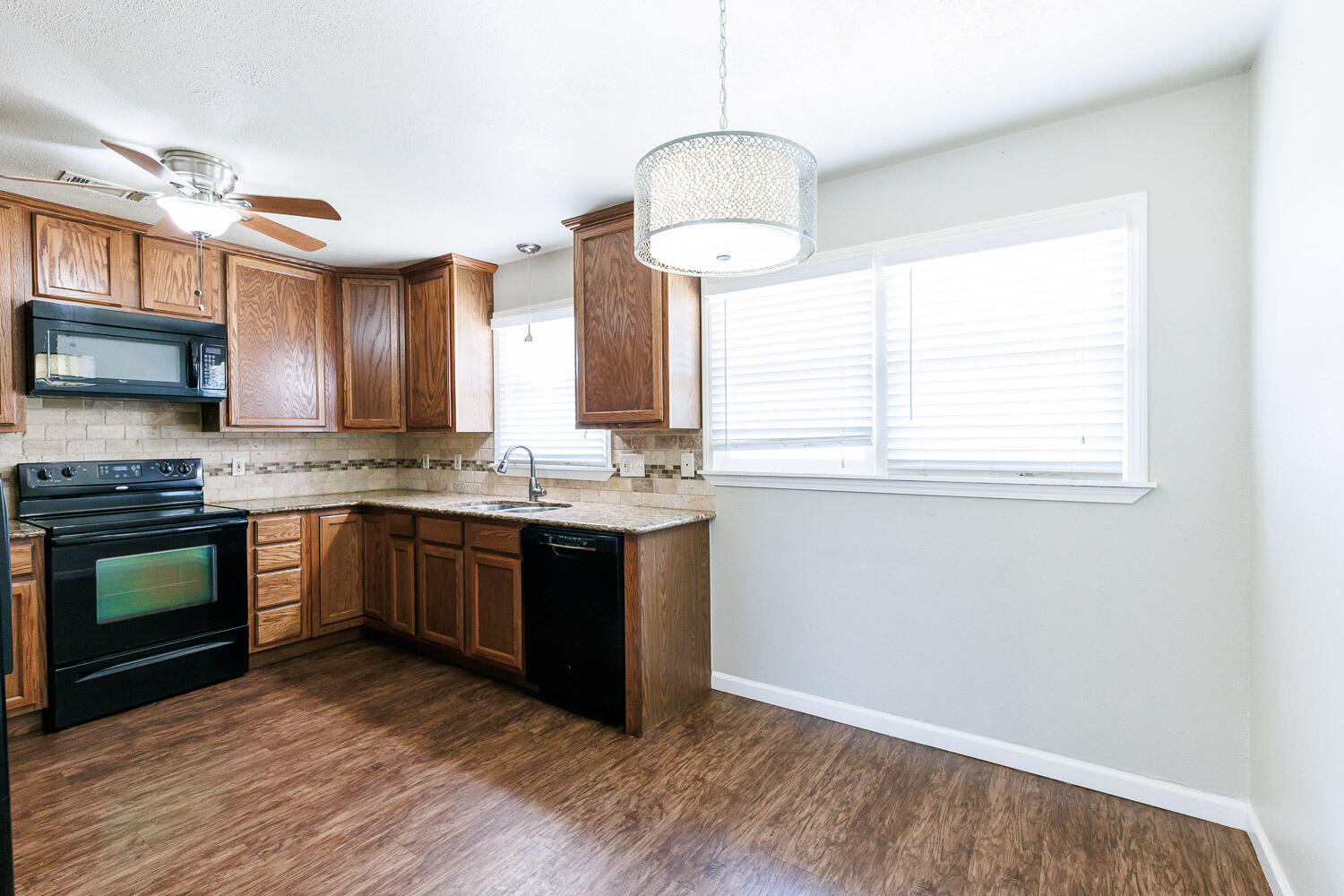 4816 45th Street Lubbock, TX 79414 - Photo 12 of 36 a kitchen with granite countertop a stove a sink and a window