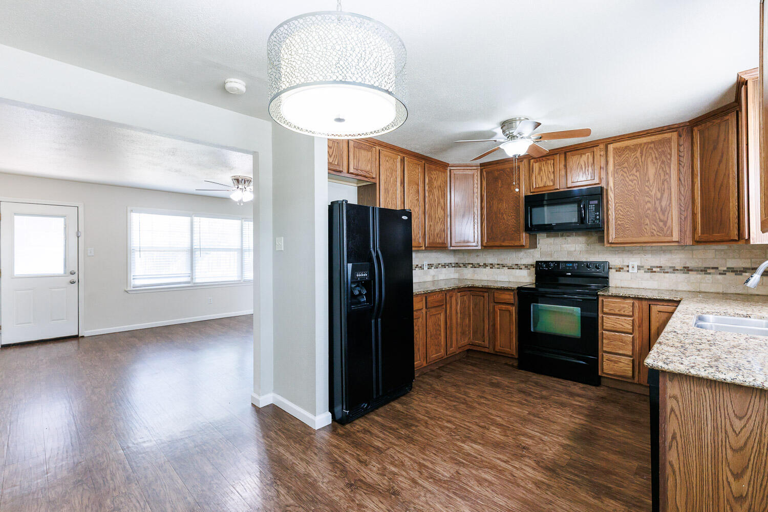 4816 45th Street Lubbock, TX 79414 - Photo 17 of 36 a kitchen with granite countertop wooden floors stainless steel appliances a sink and a window
