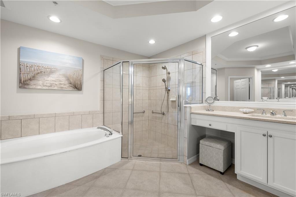 1635 Winding Oaks Way, Unit 101 Naples, FL 34109 - Photo 18 of 37 a bathroom with a bathtub a shower a sink and a mirror