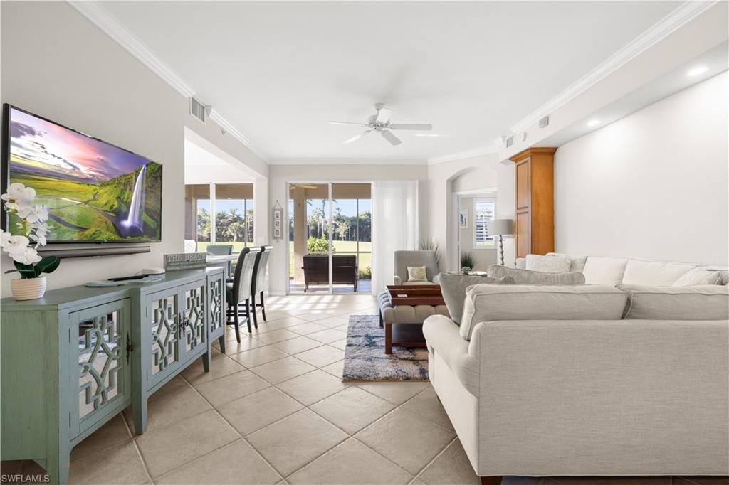 1635 Winding Oaks Way, Unit 101 Naples, FL 34109 - Photo 2 of 37 a living room with furniture a flat screen tv and a floor to ceiling window