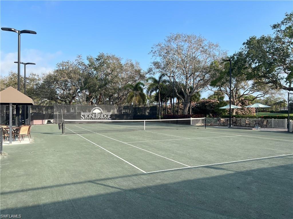 1635 Winding Oaks Way, Unit 101 Naples, FL 34109 - Photo 34 of 37 a view of a tennis ground with large trees