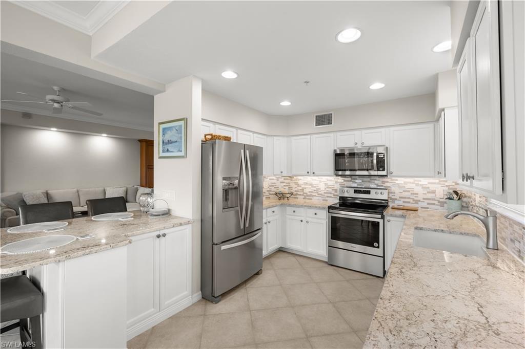 1635 Winding Oaks Way, Unit 101 Naples, FL 34109 - Photo 7 of 37 a kitchen with stainless steel appliances granite countertop a refrigerator stove microwave and sink