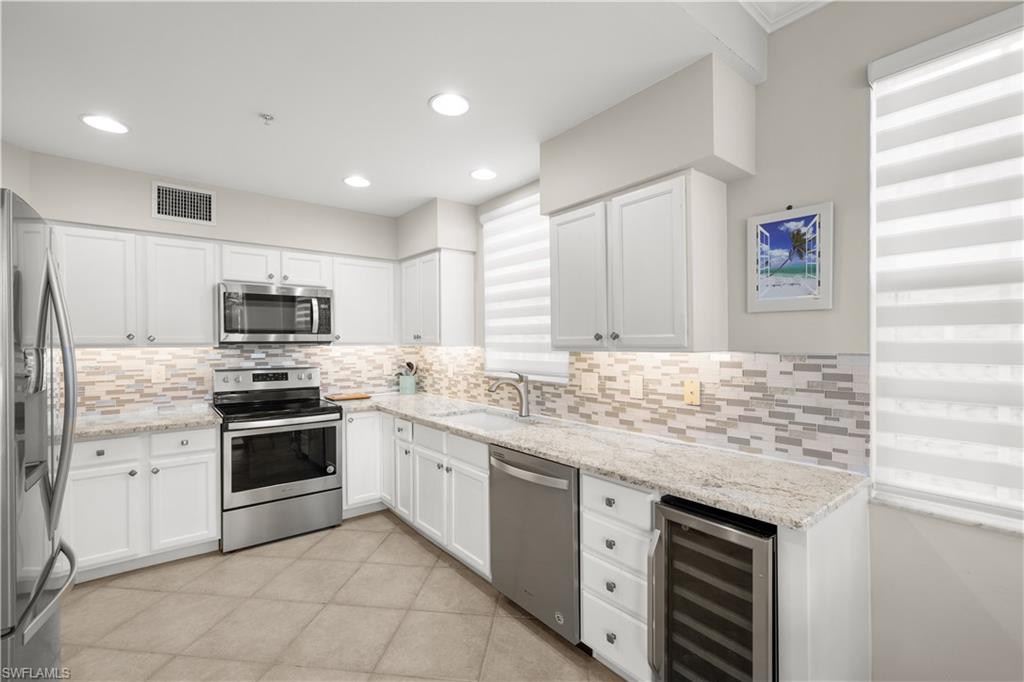 1635 Winding Oaks Way, Unit 101 Naples, FL 34109 - Photo 8 of 37 a kitchen with stainless steel appliances granite countertop a stove and cabinets