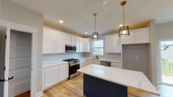 a kitchen with stainless steel appliances kitchen island a sink a stove a refrigerator and white cabinets