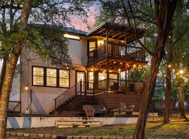 a front view of a house with large trees