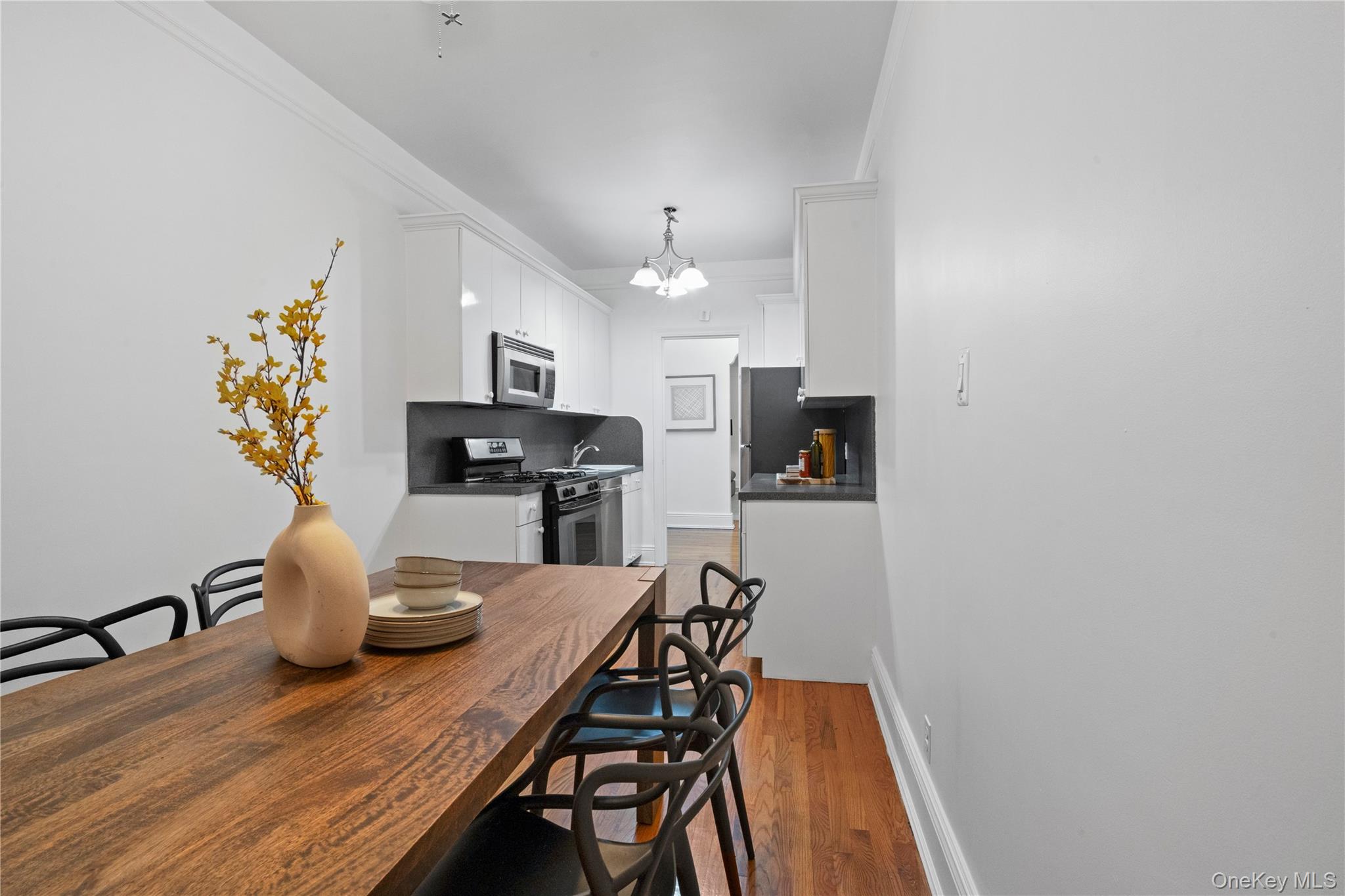 110-21 73rd Road, Unit 5H Queens, NY 11375 - Photo 7 of 14 Dining area with light wood-type flooring, ornamental molding, and a chandelier