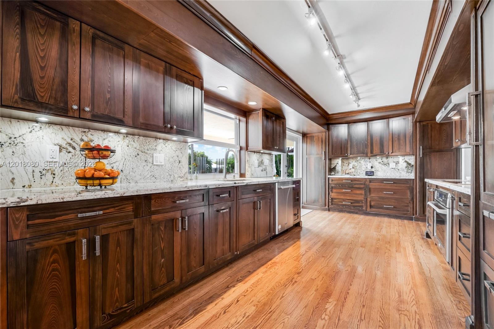 13035 Nevada Street Coral Gables, FL 33156 - Photo 7 of 21 a kitchen with stainless steel appliances wooden floors and wooden cabinets