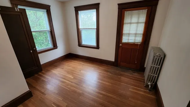 an empty room with wooden floor and windows