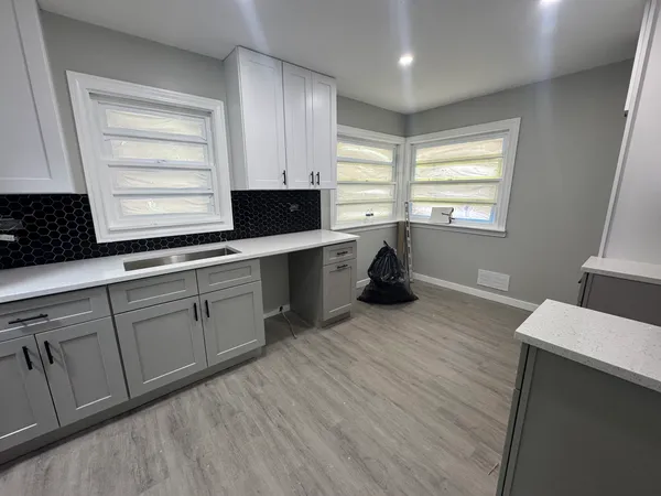 a kitchen with stainless steel appliances granite countertop a sink dishwasher a stove and a refrigerator with wooden floor