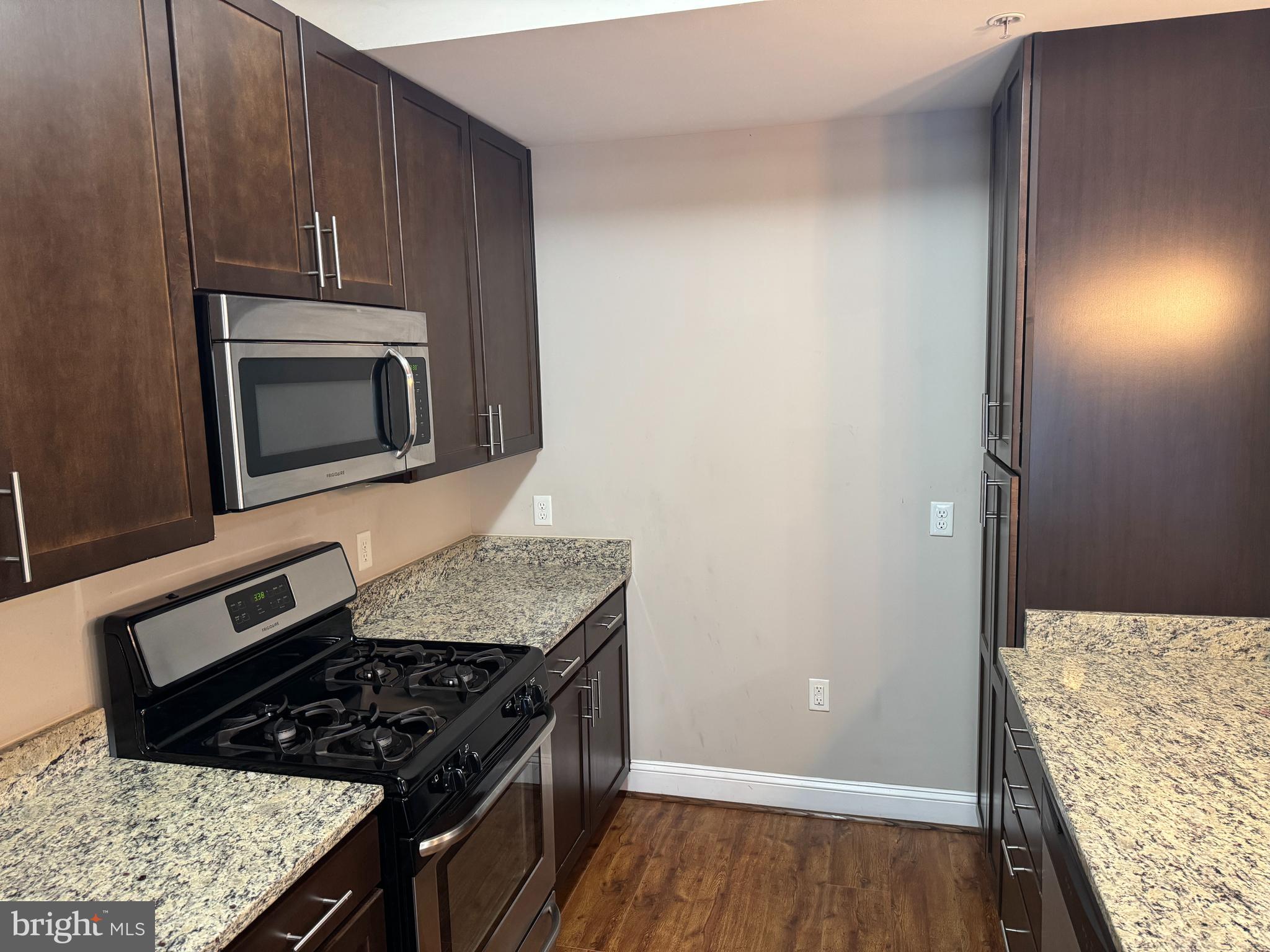 6301 Edsall Road, Unit 102 Alexandria, VA 22312 - Photo 8 of 24 a kitchen with granite countertop a stove and a microwave with wooden floor