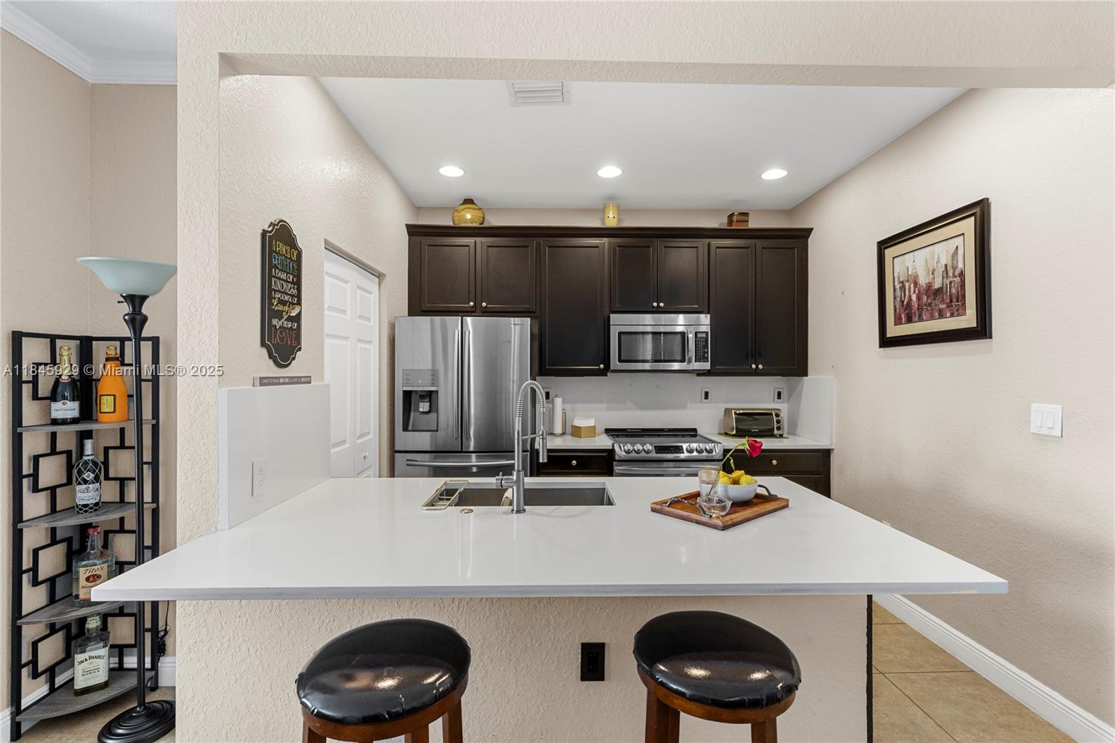 1112 Southwest 146th Terrace Pembroke Pines, FL 33027 - Photo 11 of 42 a kitchen with stainless steel appliances a stove a sink a refrigerator and cabinets
