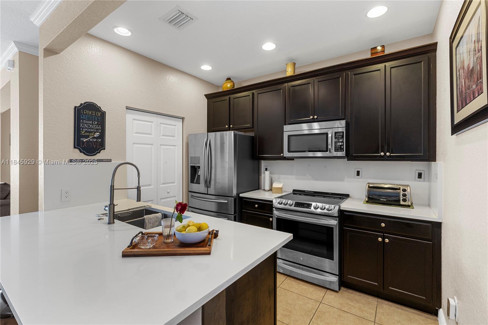 1112 Southwest 146th Terrace Pembroke Pines, FL 33027 - Photo 7 of 42 a kitchen with stainless steel appliances a stove a sink a refrigerator and cabinets