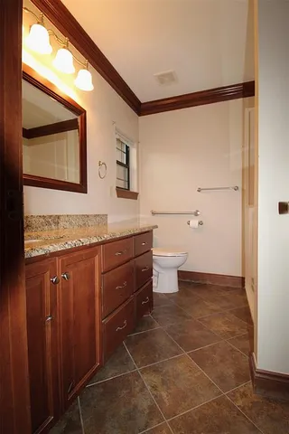 a bathroom with a granite countertop sink toilet and mirror