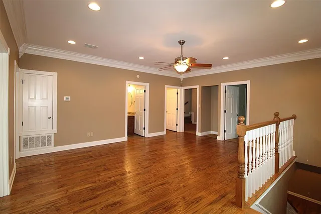 a view of an empty room with wooden floor and stairs