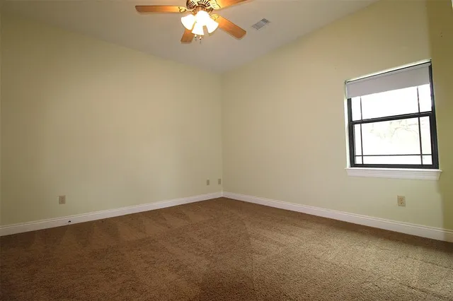 an empty room with a chandelier fan and windows