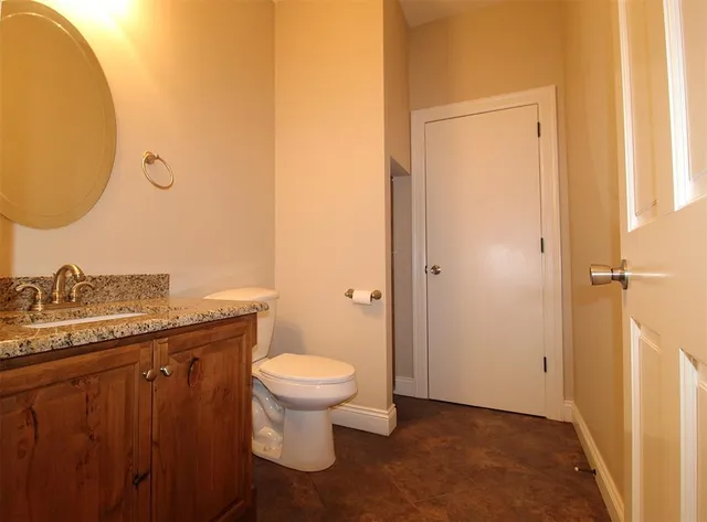 a bathroom with a granite countertop sink toilet and a mirror