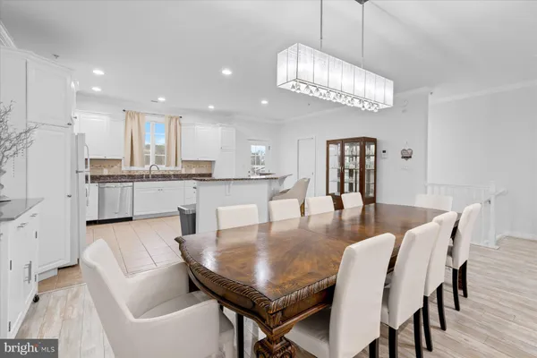 a dining room with kitchen island stainless steel appliances kitchen island granite countertop a dining table chairs and a kitchen view