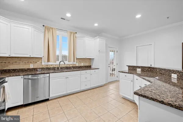 a large kitchen with granite countertop a sink and white cabinets