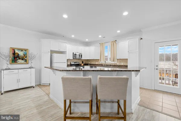a kitchen with stainless steel appliances granite countertop a table chairs sink refrigerator and microwave
