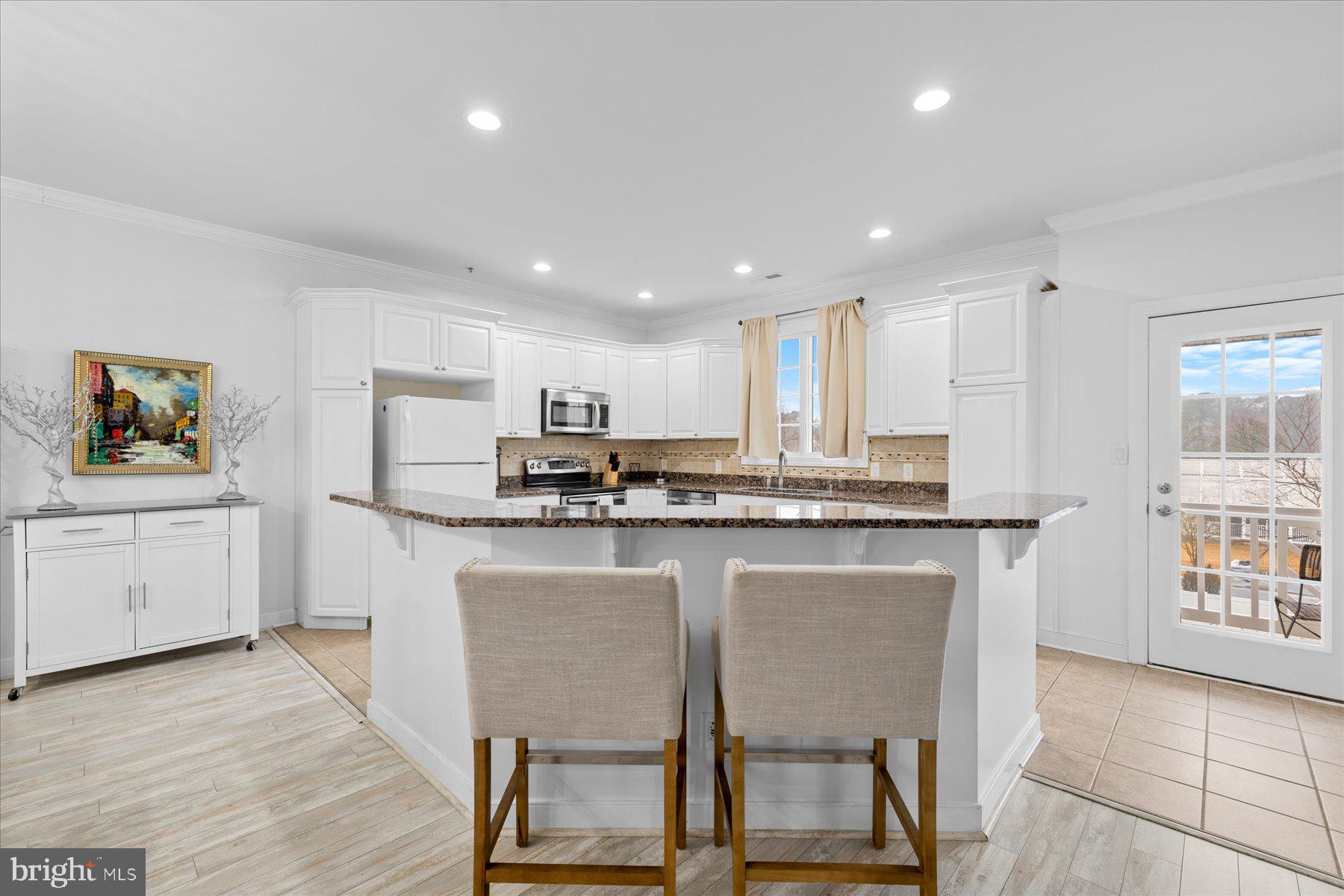 9823 Golf Course Road, Unit 10 Ocean City, MD 21842 - Photo 32 of 40 a kitchen with stainless steel appliances granite countertop a table chairs sink refrigerator and microwave