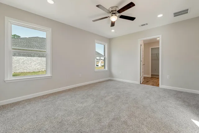 an empty room with windows and fan