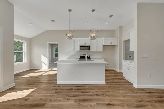 a view of kitchen with stainless steel appliances granite countertop stove top oven and cabinets