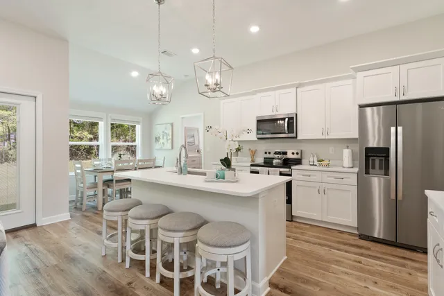 a kitchen with stainless steel appliances granite countertop a dining table chairs refrigerator and microwave