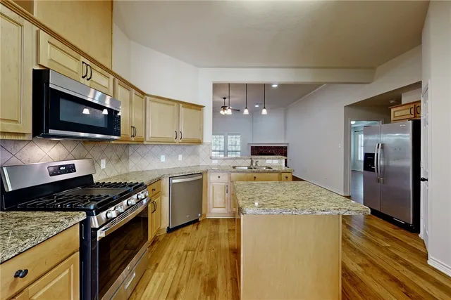 a large kitchen with stainless steel appliances granite countertop a stove refrigerator and a microwave