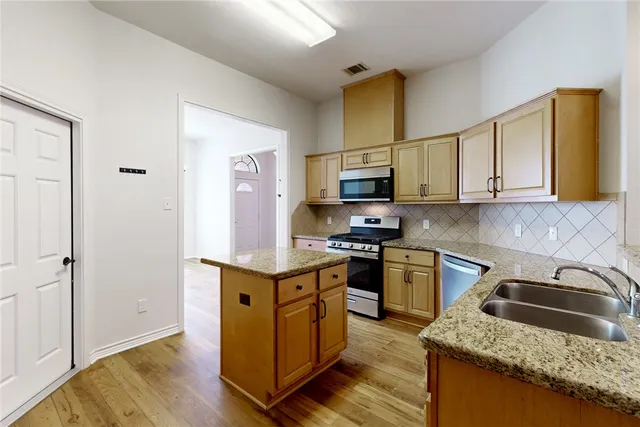 a kitchen with stainless steel appliances granite countertop a sink stove and refrigerator
