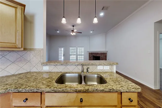 a kitchen with kitchen island granite countertop a sink a counter top space cabinets and stainless steel appliances