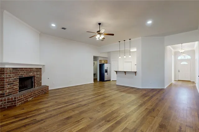 a view of an empty room with wooden floor fireplace and a window